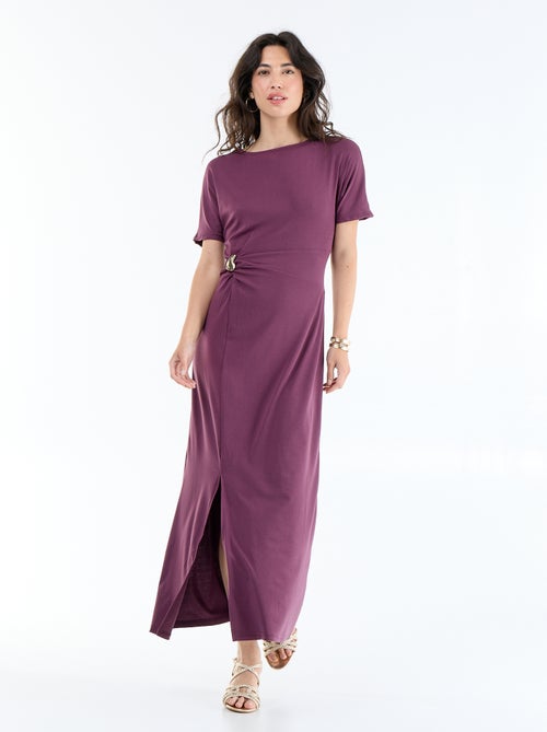 Langes Kleid mit Plisseefalten und gehämmerter Goldbrosche. - Kiabi